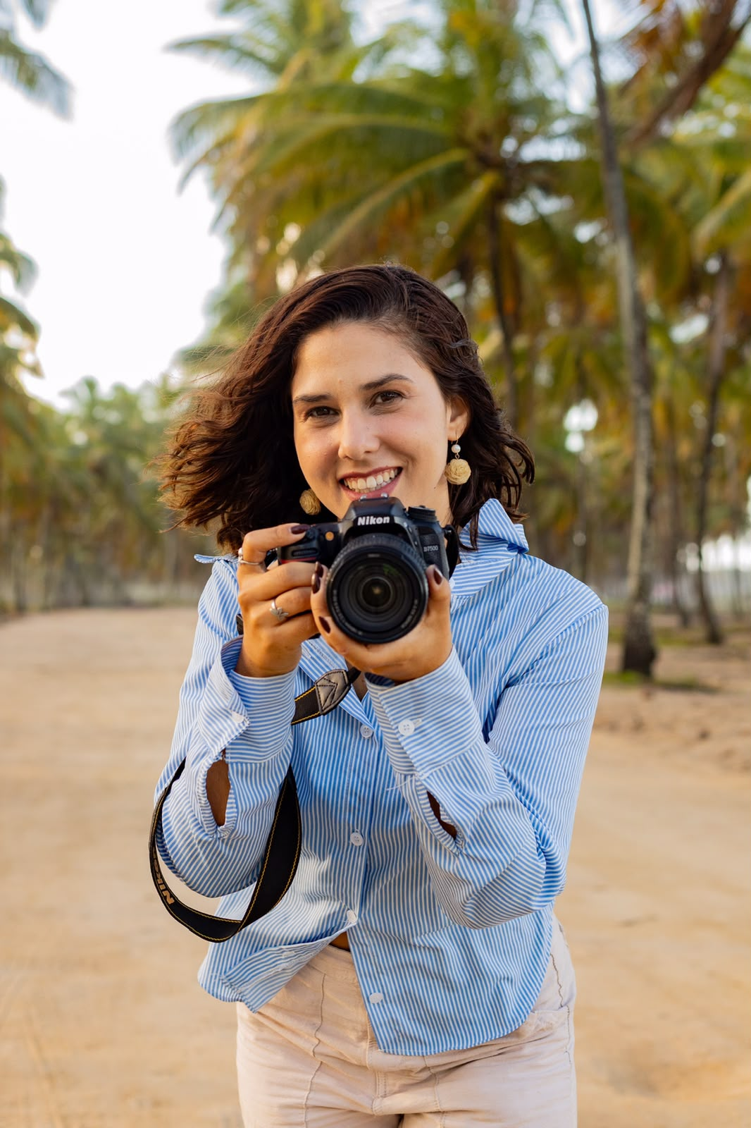 Carol Oliva com camera fotografica em praia de coqueiros